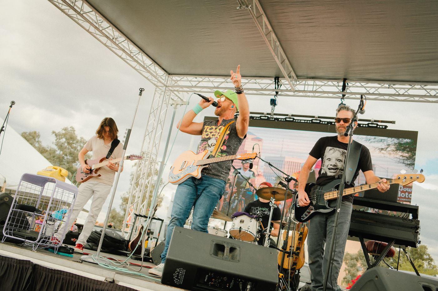 Pop Up Rebellion on an outdoor festival stage, singer pointing to the sky